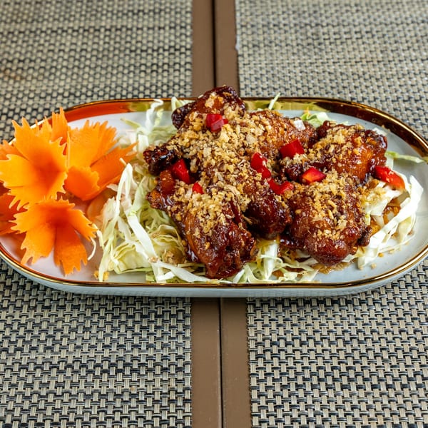 Crispy chicken wings with garlic and chili, served on shredded cabbage with carrot garnish.