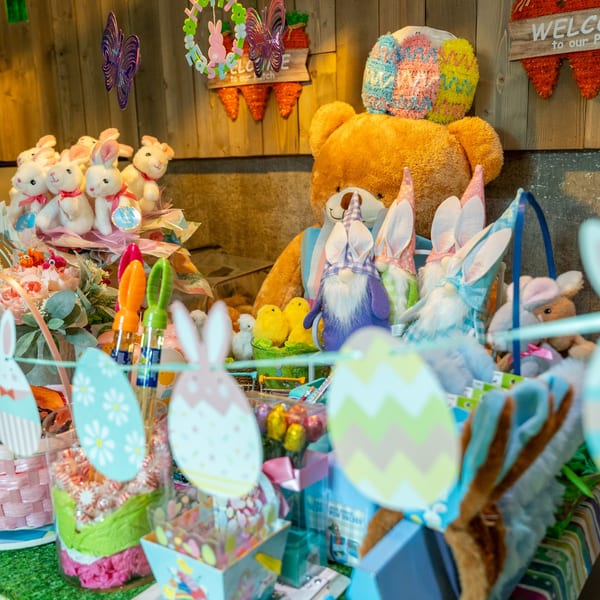 A display of Easter decorations, including plush bunnies, gnomes, candy, and a large teddy bear.