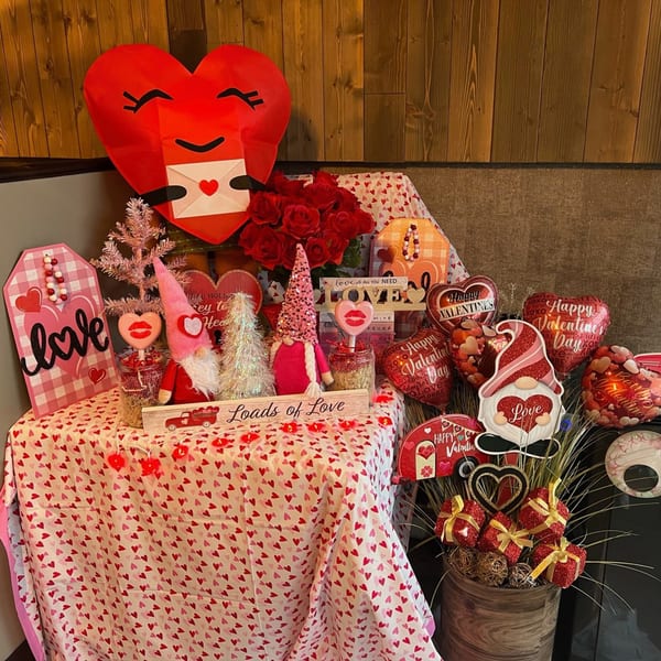 A table adorned with various Valentine's Day decorations, including gnomes, hearts, and balloons.